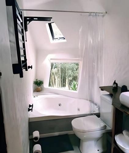 a bathroom with a tub and a toilet and a window at Diamond Cabin in the Forest | Hot Tub | AC | Fire Pit in Gonçalves