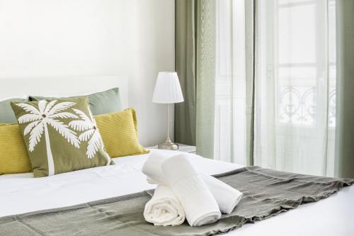 a white bed with a towel on it next to a window at Bica Palace - Residence in Center of Lisbon in Lisbon