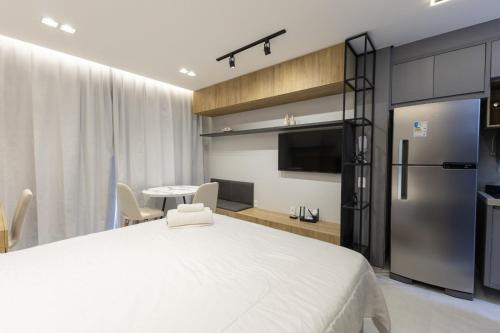 a bedroom with a white bed and a kitchen at City House 204 in Barreiras