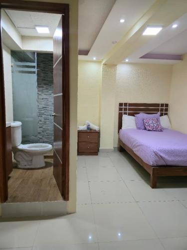 a bedroom with a bed and a bathroom with a toilet at HOTEL PUEBLO BONITO in Zacatlán
