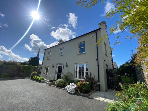 a white house with the sun in the sky at Bramley House-5 Star-located on the Dublin-Belfast corridor in Loughbrickland