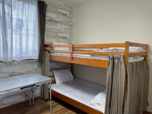 a room with two bunk beds and a desk at Guest House Goofy in Hyuga