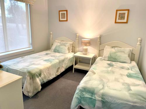a bedroom with two beds next to a window at Bay-Ann Cottage in Kingscote