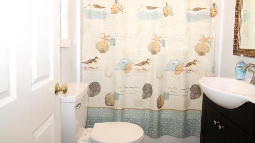 a bathroom with a shower curtain with a toilet and a sink at Shell Shack in Villas