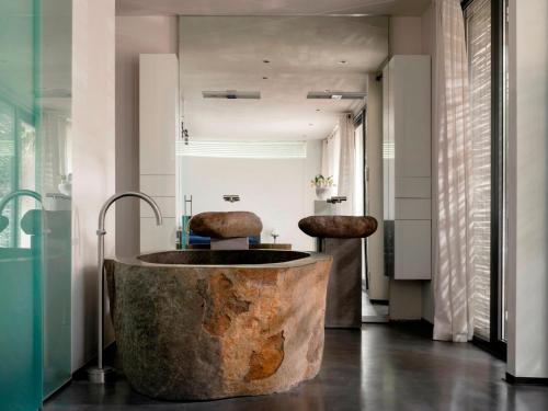 a bathroom with a large stone tub with two chairs at Wellness Villa with Private Spa in Oosterhout