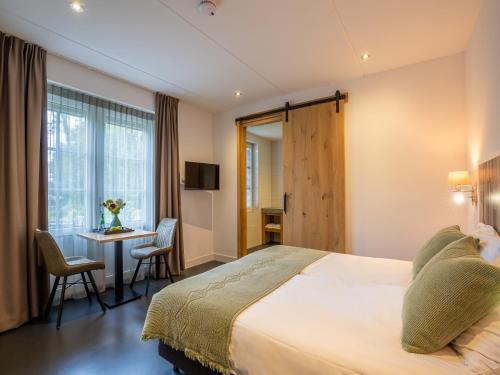 a hotel room with a bed and a table with chairs at Grand Villa with Sauna & Jacuzzi in Den Burg