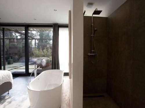 a bathroom with a white tub and a shower at Wellness Villa with Private Sauna in Oosterhout