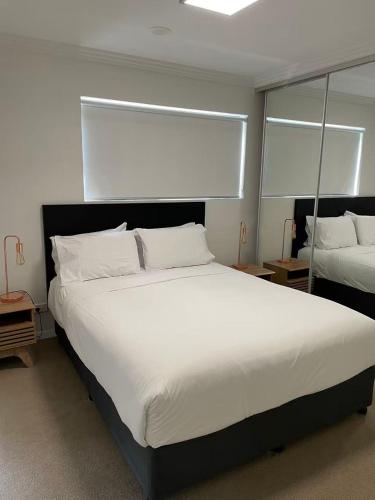 a bedroom with a large white bed and a mirror at Morgan Suites in Brisbane