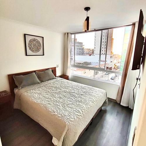 a bedroom with a bed and a large window at Edificio Lynch- Sector Centro Depto Full Equipado 2D2B Estacionamiento in Iquique