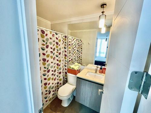 a bathroom with a toilet and a sink and a mirror at Edificio Lynch- Sector Centro Depto Full Equipado 2D2B Estacionamiento in Iquique
