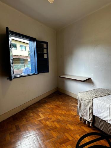 an empty room with a bed and a window at Oxx Hostel Quarto 3 in Congonhas