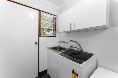 a small white kitchen with a sink and a window at Private 4BR Garden Haven - Spacious & Serene in Mawson Lakes