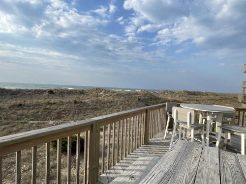 a wooden deck with a table and chairs on the beach at 57151 Lighthouse Rd Home in Hatteras