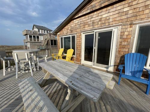 a wooden deck with a table and chairs on it at 57151 Lighthouse Rd Home in Hatteras