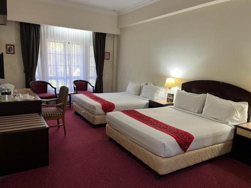 a hotel room with two beds and a desk at Hotel Seri Malaysia Genting Highlands in Genting Highlands