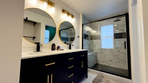a bathroom with a sink and a shower with two mirrors at Modern Luxury Haven in Colorado Springs