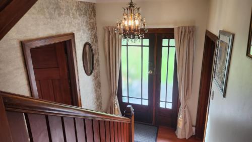a hallway with a staircase and a chandelier at La Casa in Napier