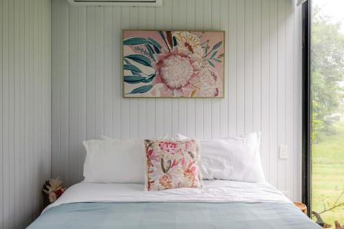 a bedroom with a bed with a picture on the wall at Deloraine Tiny Retreat by Tiny Away in Whangarei