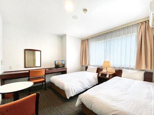 a hotel room with two beds and a desk at Hotel Grand Plaza Urashima in Kurihara