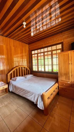 a bedroom with a bed in a wooden room at CABAÑA RaNCH OXAPAMPA in Oxapampa