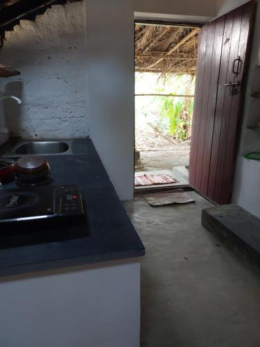 a kitchen with a counter and a sink and a door at Alumpara House - Home Stay in Palakkad