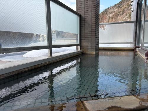 a pool of water in a room with windows at フューデイズコンドミニアム定山渓102号室 in Jozankei
