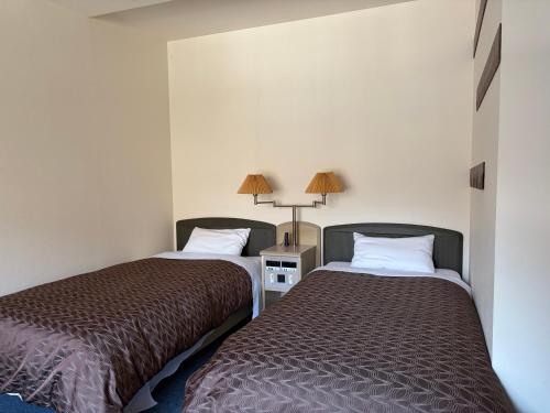 two beds sitting next to each other in a room at フューデイズコンドミニアム定山渓102号室 in Jozankei