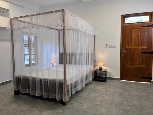 a bedroom with a canopy bed and a wooden door at Bella Nilaveli Beach in Nilaveli