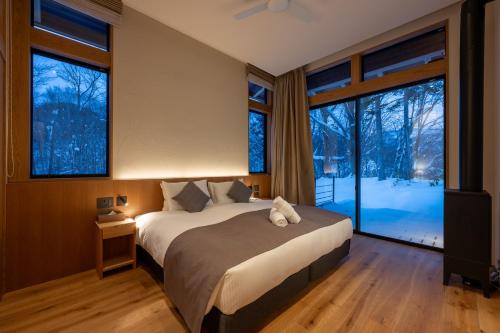 a bedroom with a large bed and large windows at Kogetsu To 湖月燈 in Lake Toya