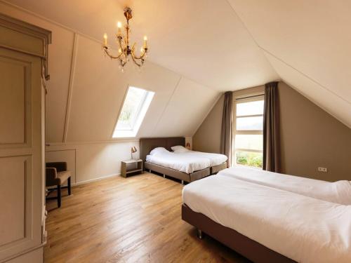 a attic bedroom with two beds and a chandelier at Achterhoek Villa with Heated Pool in Aalten
