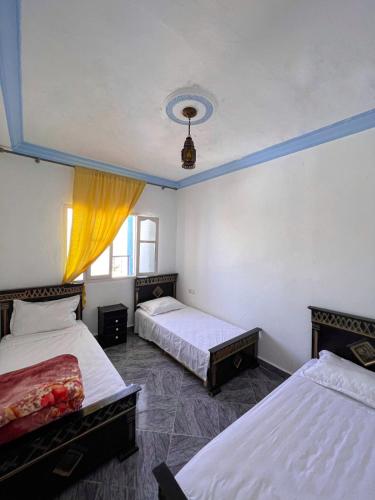 a bedroom with two beds and a blue ceiling at Casa Sharawy in Chefchaouen