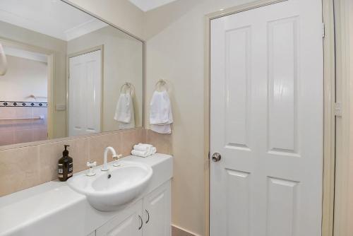 a white bathroom with a sink and a mirror at Bluewater at Mannering Park in Mannering Park