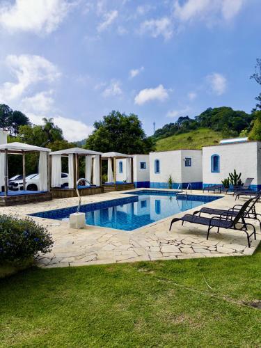 a swimming pool with two benches in a yard at Pousada Santorini Guararema in Guararema