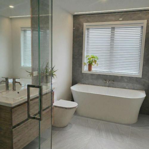 a bathroom with a tub and a toilet and a sink at Mount Pisa View Stay - Barnd new holiday home in Cromwell