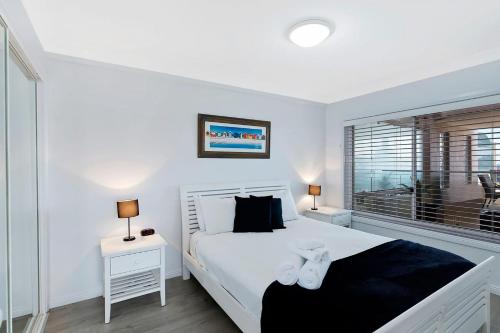 a white bedroom with a bed and a window at Ocean Pines Apartments 4 in The Entrance