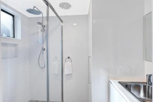 a shower with a glass door next to a sink at Ocean Pines Apartments 4 in The Entrance