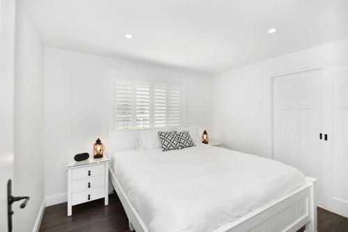 a white bedroom with a white bed and a window at Margaret's Hamptons Beach House in Hawks Nest