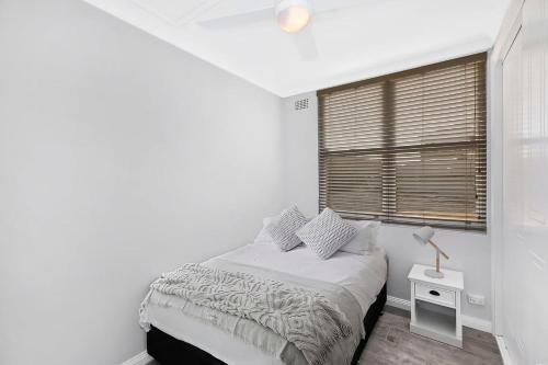 a white bedroom with a bed and a window at Golden Sands Apartment 10 in The Entrance