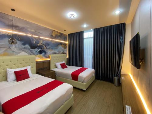 a hotel room with two beds and a tv at RedDoorz Plus at edOtel Malang in Betek