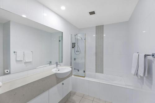 a white bathroom with a sink and a shower at Coast Apartments 19 Roof Top Pool in The Entrance