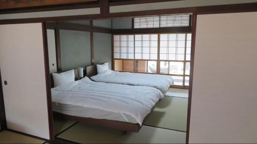 a bedroom with a large bed with a glass wall at 尾上邸 日本遺産の一棟貸し 離島の宿 in Marugame