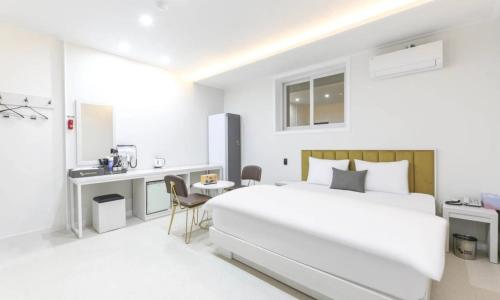 a white bedroom with a large bed and a desk at Gimcheon Sweet Hotel in Kimch'ŏn