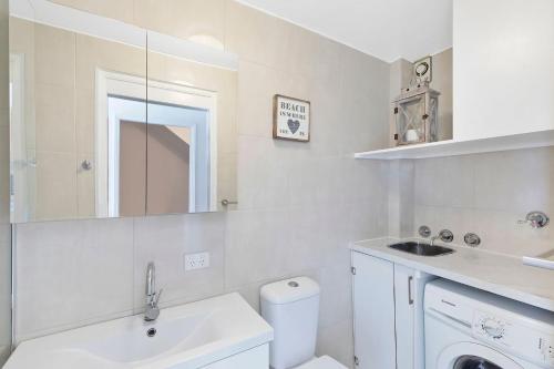 a white bathroom with a sink and a mirror at Pacific Breeze 11 in Blue Bay 