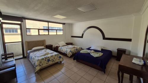 a room with two beds and a table and windows at Hotel la Ermita in Las Victorias
