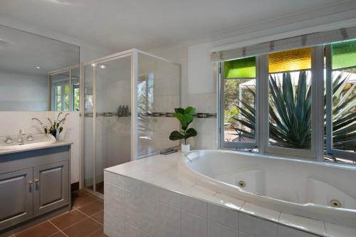 a white bathroom with a tub and a sink at Oscars in Hepburn Springs