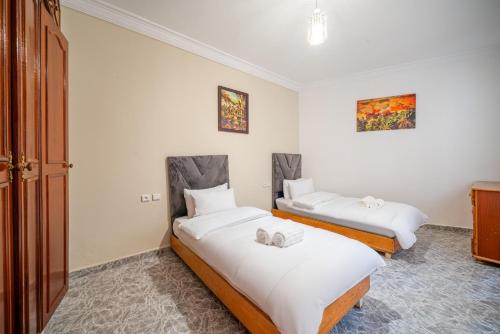 two beds in a room with white walls at Spacious Apartment 1 min from Beach in Tangier