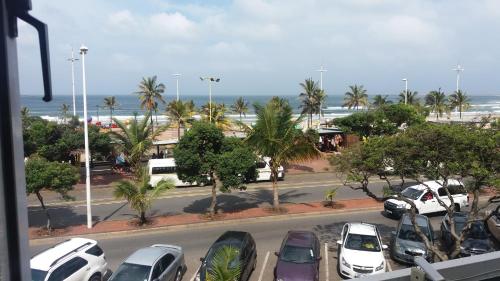a parking lot with cars parked in front of a beach at The Balmoral - Halaal in Durban