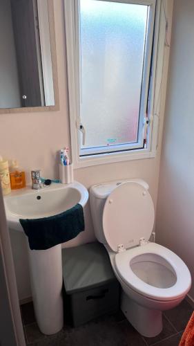 a bathroom with a toilet and a sink and a window at Beach getaway in King's Lynn