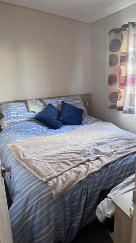 a bed in a room with blue pillows on it at Beach getaway in King's Lynn