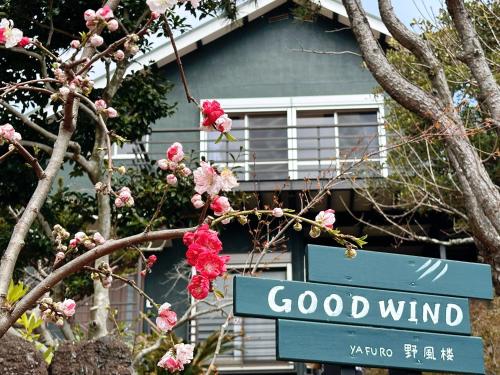 a street sign in front of a house with pink flowers at good wind 野風楼 in Yawatano